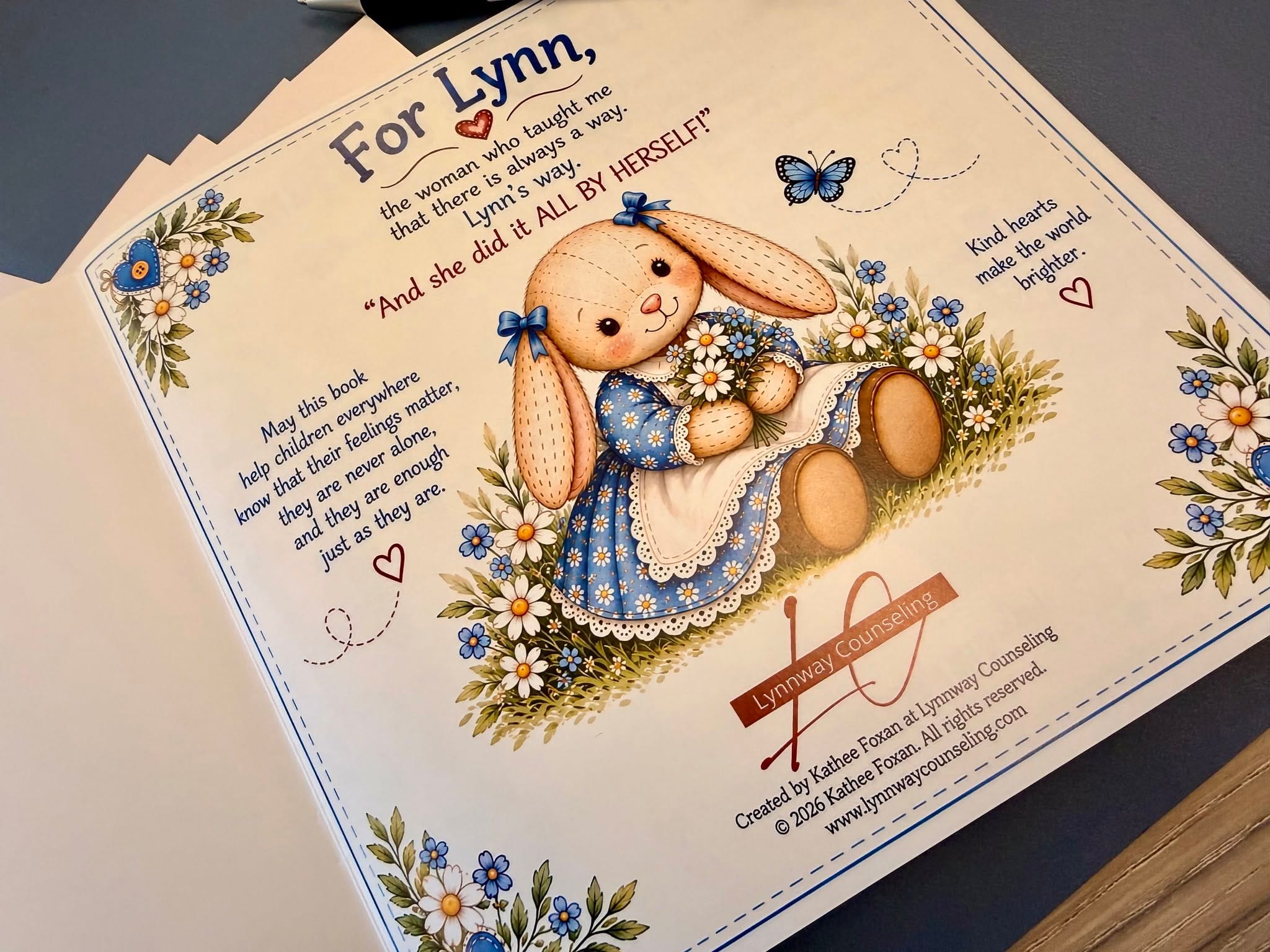 The book's dedication page. Lynn the Bunny holds a bouquet of daisies and blue flowers. The text reads: For Lynn, the woman who taught me that there is always a way. Lynn's way. And she did it ALL BY HERSELF!